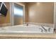 Close up of bathtub featuring a corner placement, glass shower door, and tile surround at 7240 W Grovers Ave, Glendale, AZ 85308