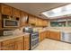 Well-maintained kitchen with oak cabinets, modern appliances, tile backsplash, and lots of natural light through the skylight at 7240 W Grovers Ave, Glendale, AZ 85308