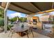 Relaxing outdoor patio with a dining table and chairs, a built-in grill, and lush landscaping creating a private retreat at 7240 W Grovers Ave, Glendale, AZ 85308