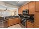 Kitchen featuring wooden cabinetry, stainless steel appliances, stone countertops, and a view into the living room at 829 S Roanoke St, Gilbert, AZ 85296