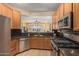 Open kitchen featuring stainless steel appliances, stone countertops, wood cabinets, and an open view into the living area at 829 S Roanoke St, Gilbert, AZ 85296