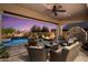 Relax on the covered patio with a fireplace, fan, and views of the pool and fire pit at 8733 E Jacaranda St, Mesa, AZ 85207