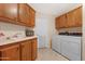 Functional laundry room features a utility sink, washer, dryer, and plenty of wood cabinet storage space at 9349 E Navajo Pl, Sun Lakes, AZ 85248