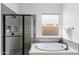 Modern bathroom showcasing a glass-enclosed shower and a soaking tub by a window at 948 E La Mirada Dr, Phoenix, AZ 85042