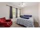 Well-lit bedroom features a ceiling fan, large windows, carpet flooring, and a comfortable red chair at 10561 E Plata Ave, Mesa, AZ 85212