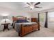 This cozy bedroom features an elegant wooden bed frame, soft carpet, and a ceiling fan at 10561 E Plata Ave, Mesa, AZ 85212