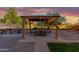 Cozy covered patio featuring string lights, comfortable seating, and a lush green backdrop at 10561 E Plata Ave, Mesa, AZ 85212