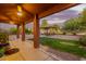 Covered patio area offers shade and space, overlooking the lush backyard with mature trees at 10561 E Plata Ave, Mesa, AZ 85212