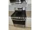 Close up of stainless steel stove, range hood, and gray backsplash at 14224 W Hackamore Dr, Surprise, AZ 85387