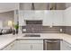 Bright kitchen featuring white cabinetry, gray backsplash, stainless steel appliances, and a modern faucet at 14250 W Wigwam Blvd # 2126, Litchfield Park, AZ 85340