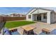 Landscaped backyard featuring lush artificial grass, a paver patio, and outdoor seating area at 14269 W El Cortez Pl, Surprise, AZ 85387