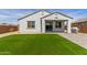 Backyard featuring a well-manicured artificial lawn that meets the white stucco exterior with covered patio at 14269 W El Cortez Pl, Surprise, AZ 85387