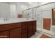 Well-lit bathroom with a double sink vanity, framed mirror, and a glass-enclosed shower at 14269 W El Cortez Pl, Surprise, AZ 85387