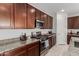 Modern kitchen featuring granite countertops, stainless steel appliances, and dark wood cabinets at 14269 W El Cortez Pl, Surprise, AZ 85387