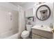 Bathroom featuring tub and shower combination, white cabinetry, and a round mirror at 15395 W Pinchot Ct, Goodyear, AZ 85395
