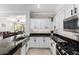 Bright kitchen with white cabinets, stainless steel appliances, breakfast bar and views into the living room at 15471 W Post Cir, Surprise, AZ 85374