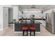 Open kitchen features an island with stool seating, stainless steel appliances, white cabinets and brick backsplash at 15471 W Post Cir, Surprise, AZ 85374