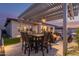 Covered outdoor patio featuring dining and seating area with pergola overlooking the pool and relaxing firepit at 17710 W Guthrie St, Surprise, AZ 85388