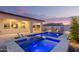 Backyard pool and patio area with a covered outdoor kitchen, lounge chairs, and vibrant blue lighting for evening swims at 17710 W Guthrie St, Surprise, AZ 85388