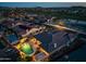 Beautiful twilight aerial view showcasing a house with a lit pool and backyard in a residential neighborhood at 18126 W Ocotillo Ave, Goodyear, AZ 85338