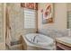 Inviting soaking tub with tile surround, accent window, and stylish fixtures at 18126 W Ocotillo Ave, Goodyear, AZ 85338