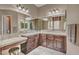 Spacious bathroom featuring dual sinks with wood cabinets, large mirrors, and a makeup vanity at 18126 W Ocotillo Ave, Goodyear, AZ 85338