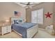 A cozy bedroom with a queen bed, patriotic decor, ceiling fan, and natural light at 18126 W Ocotillo Ave, Goodyear, AZ 85338