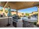 Outdoor kitchen featuring built-in grill, bar with seating under a pergola at 18126 W Ocotillo Ave, Goodyear, AZ 85338