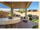 An outdoor kitchen with a bar under a pergola, next to a brick fireplace at 18126 W Ocotillo Ave, Goodyear, AZ 85338
