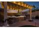 Backyard kitchen with a stone counter, built in grill, a cozy fireplace, and a covered patio with lights at 18126 W Ocotillo Ave, Goodyear, AZ 85338