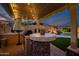 Outdoor cooking area with a grill, bar, and patio, with views of the sparkling pool with waterfall feature at 18126 W Ocotillo Ave, Goodyear, AZ 85338