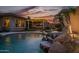 Pool view of outdoor kitchen, covered patio, waterfall, and lush landscaping at 18126 W Ocotillo Ave, Goodyear, AZ 85338