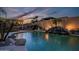 Inviting pool with rock waterfall feature, palm trees, and outdoor fireplace perfect for relaxation and entertaining at 18126 W Ocotillo Ave, Goodyear, AZ 85338