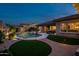 Beautiful backyard with a sparkling pool, waterfall feature, lush landscaping, and a covered patio with lounge seating at 18126 W Ocotillo Ave, Goodyear, AZ 85338