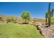 Beautiful backyard featuring a well-manicured lawn, desert landscaping, mature trees, and scenic mountain views at 2144 W Barwick Dr, Phoenix, AZ 85085