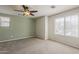 Bright bedroom with neutral carpet, a ceiling fan, and ample natural light from a large window at 2144 W Barwick Dr, Phoenix, AZ 85085