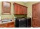 Well-equipped laundry room with sink, washer, dryer, and wood cabinets at 2335 E Allen St, Phoenix, AZ 85042