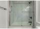 Modern tub and shower with marble tile, black fixtures and a glass door at 2511 W Queen Creek Rd # 266, Chandler, AZ 85248