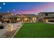 Well-maintained backyard featuring a patio with outdoor seating, lush lawn, and ambient string lights at 27203 N 78Th Ln, Peoria, AZ 85383