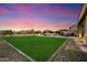 Expansive backyard with well-manicured lawn, comfortable patio seating, and romantic string lights at 27203 N 78Th Ln, Peoria, AZ 85383