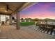 An outdoor living space offers a covered patio, lush lawn, and stunning sunset views at 27203 N 78Th Ln, Peoria, AZ 85383