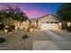 Beautiful single-story home with desert landscaping and attached garage, brightly illuminated at dusk at 27203 N 78Th Ln, Peoria, AZ 85383