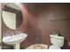 Stylish powder room featuring a pedestal sink, round mirror, and dark walls at 27316 N Covered Wagon Rd, Phoenix, AZ 85085