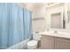 A functional bathroom featuring a shower with blue curtain and a vanity with storage at 4102 W Fallen Leaf Ln, Glendale, AZ 85310