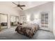 Spacious main bedroom with a ceiling fan, desk, a full-length mirror closet, and a door to the outside at 4102 W Fallen Leaf Ln, Glendale, AZ 85310