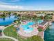 Aerial view of a community pool area, lake, and residential buildings under a bright, sunny sky at 42335 W Waterfall Way, Maricopa, AZ 85138