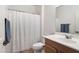 Well-lit bathroom features a shower with a white curtain and wood vanity at 42335 W Waterfall Way, Maricopa, AZ 85138