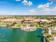 Aerial view of the clubhouse and lake featuring a patio with chairs and landscaping at 42335 W Waterfall Way, Maricopa, AZ 85138