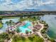 Aerial view of the pool and lake, framed by palm trees and landscaping with the mountains in the background at 42335 W Waterfall Way, Maricopa, AZ 85138