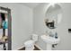 Stylish powder room with pedestal sink, oval mirror, and decorative shelving unit at 44314 W Mescal St, Maricopa, AZ 85138